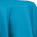 A turquoise blue tablecloth with a round top.