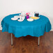 A table with a turquoise blue tablecloth, plates, and cups.