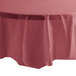 A round table with a burgundy Creative Converting OctyRound plastic table cover on top.