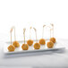 A Libbey ultra bright white rectangular porcelain tray with a row of cheese balls on toothpicks.