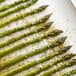 A group of asparagus spears on a baking sheet seasoned with Regal Tangy Lemon Pepper.