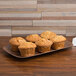 A rectangular melamine tray of muffins on a table.
