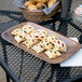 A Carlisle rectangular woodgrain melamine tray with a plate of pastries on a table in a bakery display.
