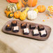 A Carlisle woodgrain melamine tray holding chocolate covered treats.