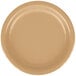 A close-up of a Creative Converting 7" glittering gold paper plate with a round edge on a tan surface.