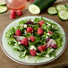 A Carlisle jade melamine salad plate with a salad of raspberries and cucumbers.
