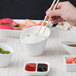 A person using chopsticks to eat from a 10 Strawberry Street white porcelain slant bowl.