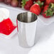A silver stainless steel Ateco food mold filled with a red dessert next to strawberries.