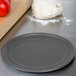 A ball of pizza dough sits on an American Metalcraft Hard Coat Anodized Aluminum Pizza Pan on a counter.