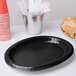 A stack of black oval paper platters on a table.