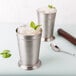 Two Libbey stainless steel mint julep cups with ice and mint in one of the cups.