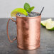 A World Tableware copper Moscow Mule mug with ice and lime wedges.