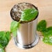 An American Metalcraft stainless steel mint julep cup filled with ice and mint leaves.