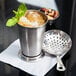 An American Metalcraft stainless steel mint julep cup with ice and mint leaves on top.
