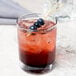 A Tablecraft bamboo heart pick in a glass of drink with blueberries on top.