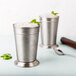 Two Libbey stainless steel mint julep cups with ice and mint in them.