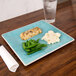 A Carlisle aqua square melamine plate with a piece of fish, green beans, and a fork on a table.