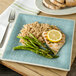 A Carlisle Aqua Square Melamine Plate with rice, chicken, and asparagus with a lemon slice on top.