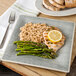 A Carlisle smoke square melamine plate with rice, chicken, and asparagus with a lemon slice on top.