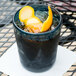 A teal Carlisle Mingle double rocks glass with ice and orange slices.