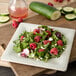 A Carlisle melamine square salad plate with a salad of raspberries and cucumbers.