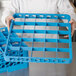 A person using a Carlisle glass rack extender on a blue tray.