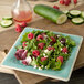 A plate of salad with raspberries and cucumbers on a Carlisle Aqua square melamine salad plate.