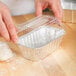 A person putting dough into a clear plastic dome lid.
