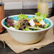 A Carlisle Aqua Melamine bowl filled with salad on a table.
