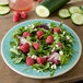 A Carlisle Aqua melamine salad plate with a salad of raspberries and cucumbers.