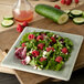 A Carlisle smoke melamine salad plate with a salad of raspberries, lettuce, and cucumbers.