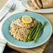 A Carlisle Aqua melamine plate with asparagus, rice, and chicken with a lemon wedge on top.