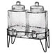 A Stylesetter glass beverage dispenser with metal stand holding two glass jars with lids.