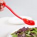 A hand holding a red Cambro salad bar spoon over a salad.