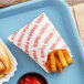A tray with a Carnival King medium French fry bag filled with french fries and a hot dog.