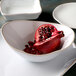 A white Tuxton Capistrano bowl with a pomegranate in it.