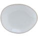 A white Tuxton china plate with an ellipse shape and a white rim.