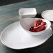 A white rectangular Tuxton Artisan china plate with a bowl of pomegranate seeds.