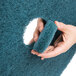 A hand holding a blue 3M 5300 floor cleaning pad.