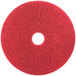 A 3M red circular floor pad with a white circle in the middle.