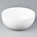 An Arcoroc white porcelain serving bowl on a gray surface.