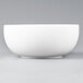 An Arcoroc white porcelain bowl on a gray background.