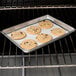 A Chicago Metallic aluminum sheet pan with a tray of cookies baking in an oven.