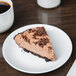A piece of chocolate pie on a Chef & Sommelier white bone china plate next to a cup of coffee.