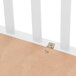 A close-up of a metal bar on the side of a white wood crib.