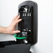 A hand opening a black plastic box with a green and black True Fit Wall Plate inside.