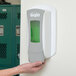 A hand holding a white and green rectangular GOJO True Fit wall plate.