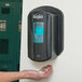 A person installing a GOJO Black True Fit wall plate for a LTX-12 hand sanitizer dispenser.