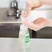 A person using a pump to dispense GOJO Green Certified Fragrance Free foaming hand soap from a plastic bottle.
