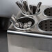 A Steril-Sil stainless steel countertop flatware organizer with spoons inside.